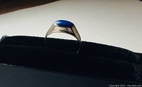 Side view of sterling silver ring with bezel-set lapis lazuli cabochon, showing blue oval stone and silver band profile.