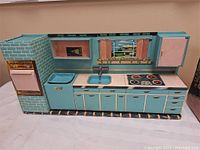 Full view of blue metal toy kitchen showing stove, sink, faucet, and cabinets.