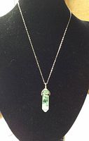 Full view of green quartz pendant on sterling silver chain displayed on black bust stand.