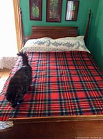 Large wool blanket laid on a double bed with a black cat sitting on it, showing size and pattern.