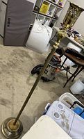 Full view of brass floor lamp showing long stem and top section with decorative brass holder.