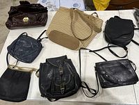 Photo of all seven purses arranged on table showing different styles and materials including leather and woven fabric.