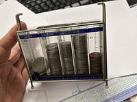 Front view of coin bank showing coins in separate compartments including halves, quarters, dimes, nickels, and cents.