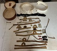 Overall lot showing all insignia and accessories laid out on a white table including hat bands, ribbons, epaulets, buttons, and patches.