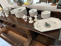 Multiple stacks of octagonal plates, bowls, mugs, sugar bowl, creamer, candlesticks and one platter on a sideboard