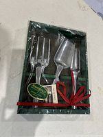 Full view of the pewter garden tool set in original green box, showing all three tools and red ribbon securing them.