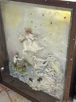 Full view of the large encaustic art sculpture depicting a mythical scene with figures, waves, and light-reflective wax textures inside a wooden shadow box frame.