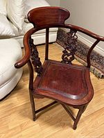 Front and side view of rosewood oriental corner chair showing curved backrest, armrests, and carved side supports.