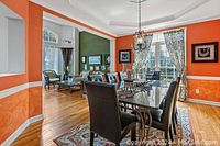 Rectangular black granite dining table with rounded ends and iron legs in a dining room with orange walls. Nearly 8 leather dining chairs are around it, no chairs included in the lot.