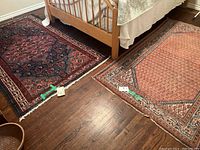 Two rugs side by side on hardwood floor under bed showing both patterns and relative sizes