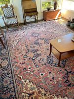 Full view of rectangular rug in living room showing coral field, navy border, furniture for scale