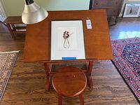 Photo of wooden art desk top with framed floral print and attached lot tag.