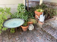 Image showing birdbath, potted plants, watering can and garden ornament on brick patio