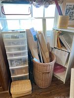 Overall lot showing plastic drawer cabinet, woven basket with rolled papers, small basket, and shelving unit with binders.