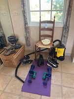 Overall photo showing chair, shoes, weights, vacuum, and decorative flower on tiled floor near window.