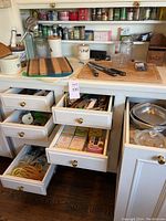 Wide view of kitchen drawer and counter with assorted kitchen cutting boards, spice jars, salt box, and kitchen utensils.
