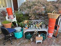 Overall view of outdoor items including the garden bench, gardening tools, buckets, chair, and decorative items arranged on brick patio.