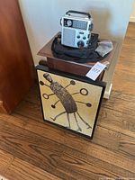 View of the side table with the portable radio on top, and framed art resting against the side of the table on wooden floor.