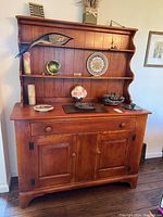 Full view of wooden sideboard with three-shelf hutch and items on top