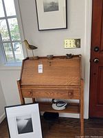 Desk closed front showing oak grain, brass hinges, top surface with decorative bird and bowl