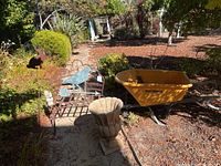 Overview of outdoor garden area showing wheelbarrow, planter, and decorative bench with bird and rabbit figures