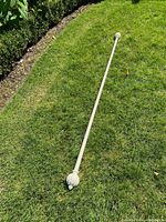 Full length view of the white antique curtain rod with one fluted finial visible on grass.