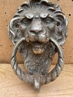 Front detailed view of the antique Lion's Head door knocker with metal ring in mouth highlighting design and condition.
