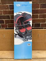 Front view of the original retail box showing a Baby Jogger double stroller equipped with the adjustable belly bar.