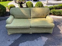 Front view of green chenille couch showing seat cushions, back cushions, and valance waterfall skirt in outdoor setting.