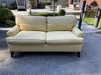 Front view of couch showing seat and back cushions, nailhead trim and spike legs