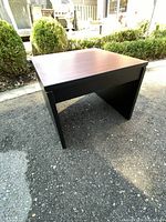 Photo of the black base home office side table with faux wood laminate top from front-left angle outdoors.
