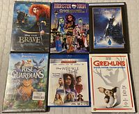 Top view of six DVD cases including Disney Pixar Brave, Monster High, The Polar Express, DreamWorks Rise of the Guardians, Disney A Wrinkle in Time, and DreamWorks Gremlins Special Edition.