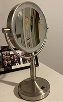 Front angle of the make-up mirror on a stand showing the reflective surface and nickel finish.