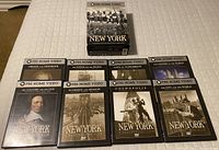Photo of 8 DVD cases from PBS series New York, lined up on a white surface showing different titles and cover images