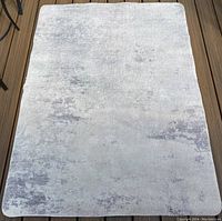 Full view of plush small area rug showing mottled blue and grey tones, rectangular shape with rounded corners.