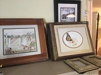 Several framed artworks by Dianne Barkey displayed together including a girl hanging laundry, butterfly artwork, and another landscape or floral piece.