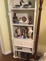 Shelf with all items including books, wooden figures, clock, key holder, cherub pictures