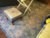 Carpet laid out with visible overall pattern showing floral and scroll designs. Some furniture legs partially visible.