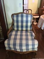 Upholstered chair front view showing blue and beige buffalo check patterned fabric upholstery and carved wooden arms.