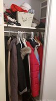 Closet view showing multiple winter coats on white plastic hangers