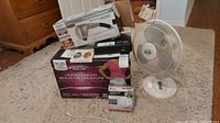Lot with fan, massager box on top, underwear box on floor, and smoke alarm box in front.