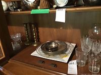 Glassware, metal candle holders, and serving plates displayed on a wooden shelf