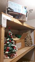 Photo showing wooden shelves with large boxes of holiday wrapping supplies and ceramic Christmas trees.
