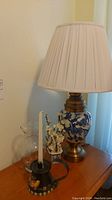 Table lamp with fabric shade, glass vase, metal candle holder with candle and artificial flowers