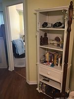 Front view of painted wooden shelf unit filled with books and decorative items, emphasizing structure and wear.