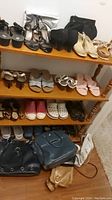 Wide view of three shelves displaying various women's shoes and several handbags placed on the bottom shelf on a beige carpet.