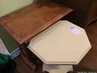 Overall view of the two side tables placed next to each other, showing the painted drop leaf table in front and the wood table behind.