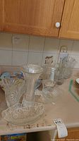 Various clear glass vases and bowls and a plastic platter on a countertop