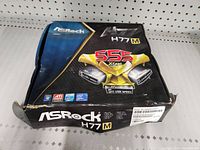 Original Asrock H77M motherboard box with signs of wear and damage