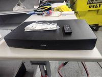 Front view of Bose Solo TV Sound System with remote and manual on top, showing the Bose logo and surface details.